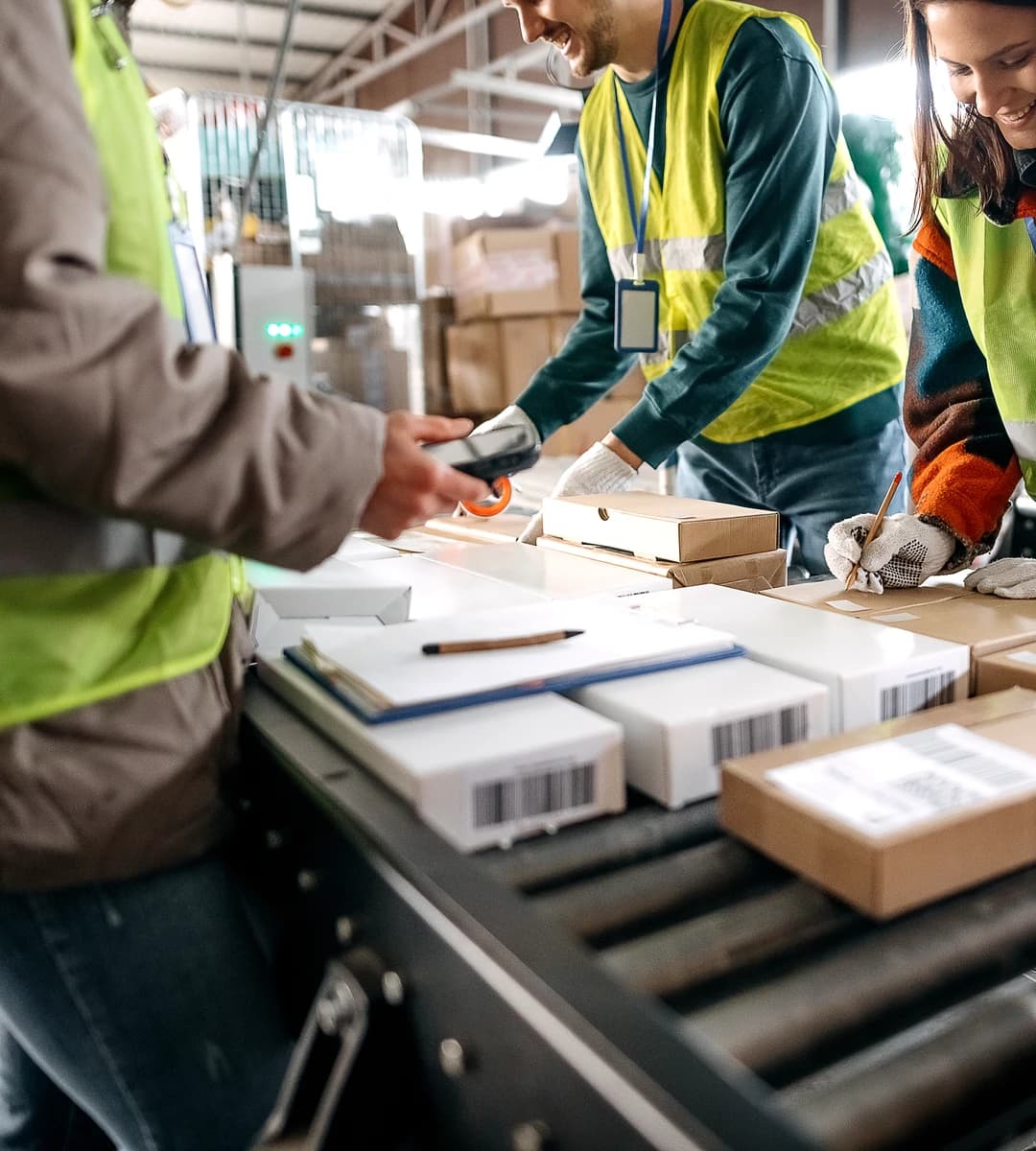 Prep centre staff scanning and labelling cartons on a conveyor line